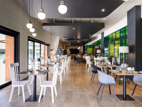 a restaurant with white chairs and tables and windows at Novotel Milano Linate Aeroporto in Milan