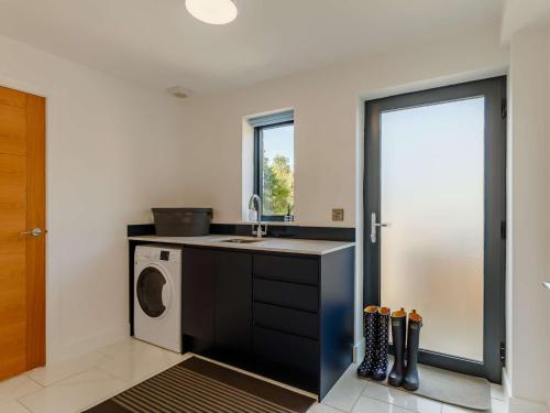 a kitchen with a sink and a washing machine at 4 Bed in Bude 89355 in Poughill