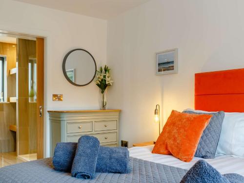 a bedroom with a bed with blue and orange pillows at 4 Bed in Bude 89355 in Poughill