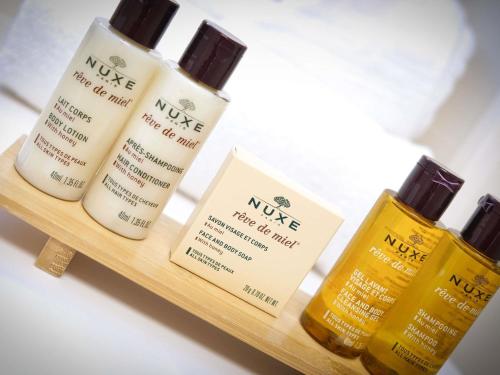 four bottles of moisturizers sitting on a wooden shelf at Mercure Perpignan Centre in Perpignan