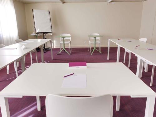a classroom with white tables and chairs and a chalkboard at Mercure Perpignan Centre in Perpignan
