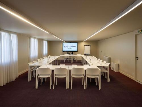a conference room with tables and chairs and a screen at Mercure Perpignan Centre in Perpignan