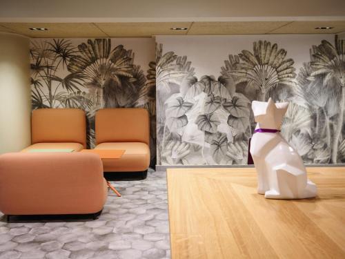 a cat sitting on the floor in a waiting room at Mercure Perpignan Centre in Perpignan