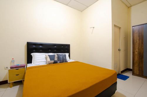 a bedroom with a yellow bed with a cross on the wall at Athena Syariah Residence in Tangerang
