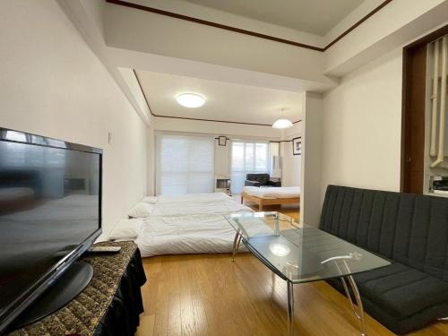 a living room with a bed and a couch and a tv at Dolce Fuji in Sapporo