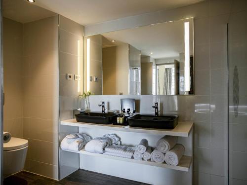 a bathroom with two sinks and a mirror and towels at Pullman Abidjan in Abidjan