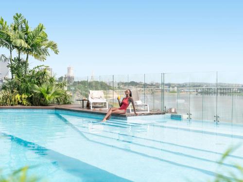 a woman sitting in a chair next to a swimming pool at Pullman Abidjan in Abidjan