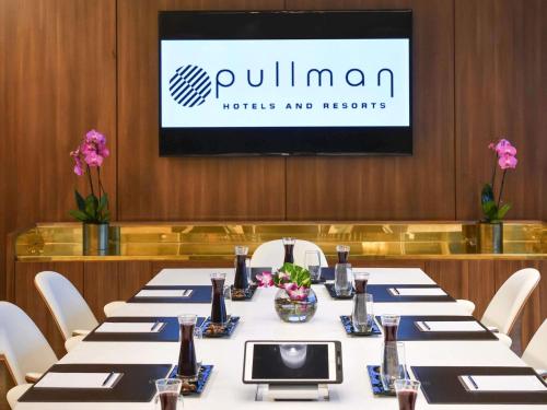 a conference room with tables and chairs and a tv at Pullman Abidjan in Abidjan