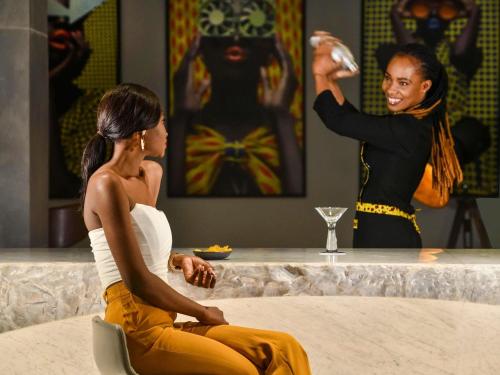 two women sitting on a bed talking to a woman standing at Pullman Abidjan in Abidjan