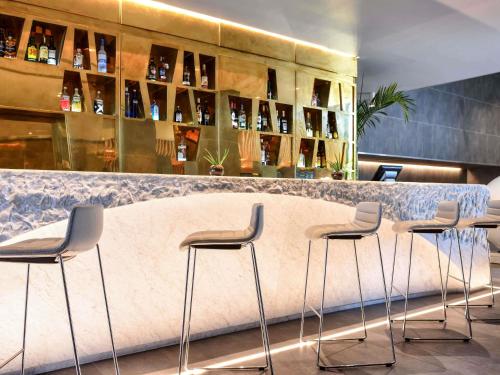 a bar with stools and bottles of wine at Pullman Abidjan in Abidjan