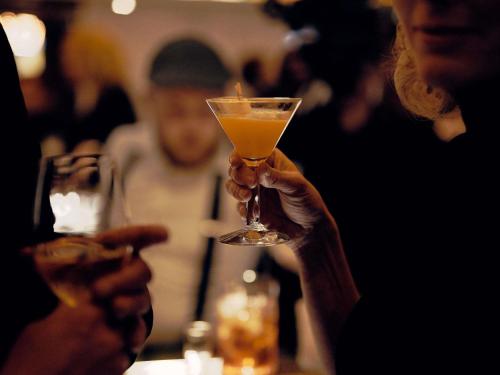 a person holding a drink in a glass at INK Hotel Amsterdam - MGallery Collection in Amsterdam