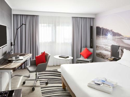 a hotel room with a bed and a desk and chairs at Novotel Birmingham Airport Terminal Building - NEC in Bickenhill