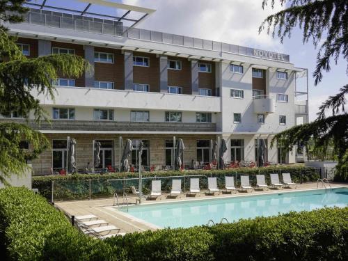 a hotel with a swimming pool in front of a building at Novotel Saint-Quentin en Yvelines in Magny-les-Hameaux