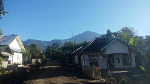 a couple of houses with mountains in the background at Tetebatu Indah Homestay in Tetebatu