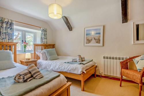 - une chambre avec 2 lits et une chaise dans l'établissement Bourne Cottage, à Weybourne