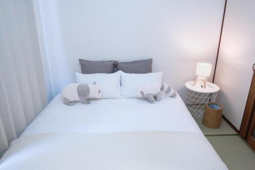 un lit blanc avec deux animaux rembourrés dans l'établissement Fukuoka Hakata Stay 1BR with Balcony, TV and Laundry, à Fukuoka