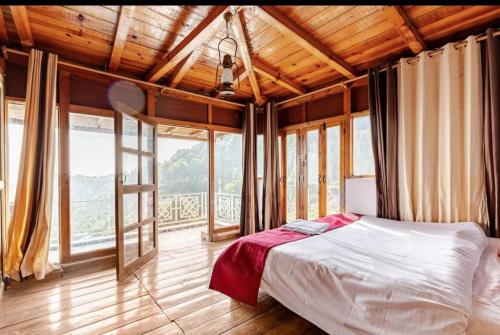 a bedroom with a bed in a room with windows at The sunrise Himalayas view cottage in Bhowāli