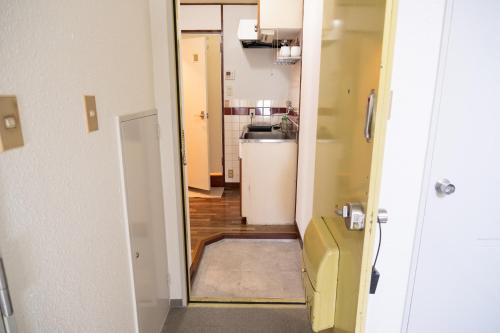 un couloir menant à une cuisine équipée d'un réfrigérateur dans l'établissement Fukuoka Hakata Stay 1BR with Balcony, TV and Laundry, à Fukuoka