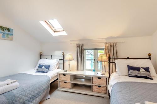 a bedroom with two beds and a desk and a window at White Rose Cottage in Bodham