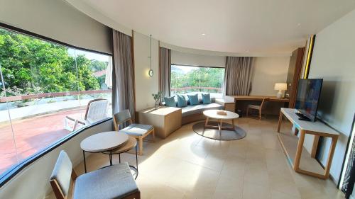 a living room with a couch and a tv at Novotel Rayong Rim Pae Resort in Klaeng