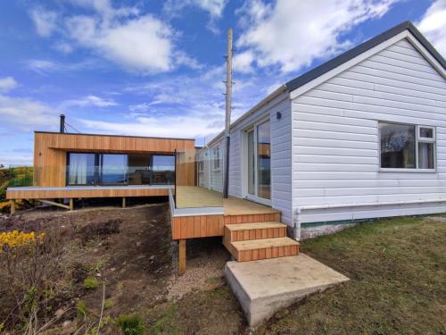 a small white house with a porch and stairs at 3 bed in Scourie SU164 in Rhiconich