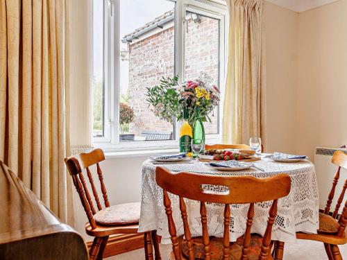 a dining room table with a vase of flowers on it at 2 Bed in Mattishall 57133 in Mattishall