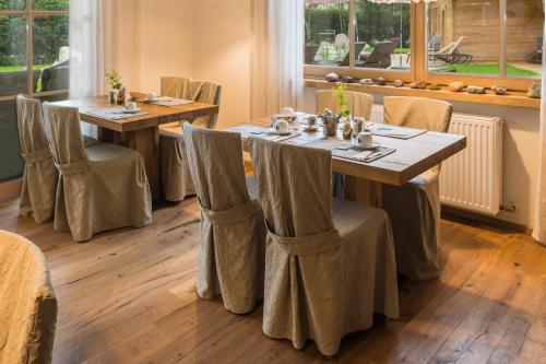 a dining room with wooden tables and chairs with curtains at Flora - Das kleine Gartenhotel in Ellmau