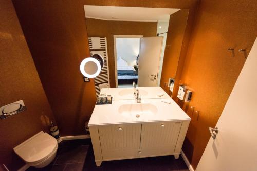 a bathroom with a sink and a toilet and a mirror at Hotel Business & More SELF CHECK IN in Hamburg