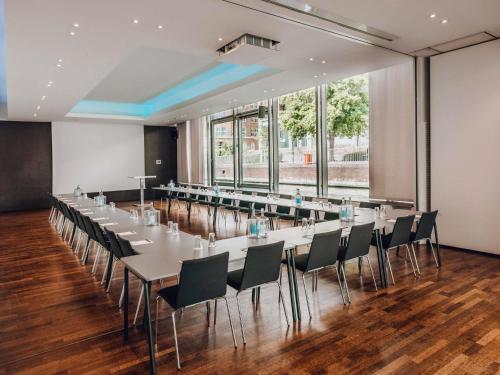 a conference room with tables and chairs and a large window at Mercure Hotel Hamburg City in Hamburg