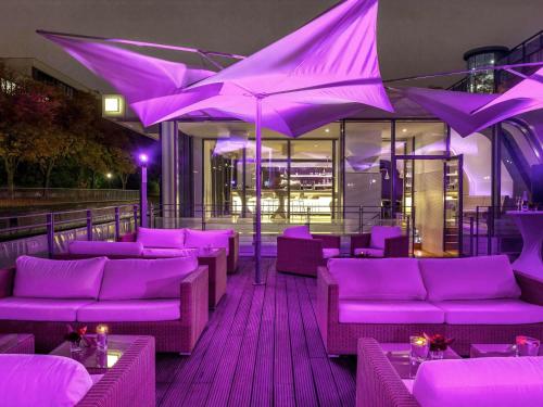 a restaurant with purple chairs and umbrellas on a deck at Mercure Hotel Hamburg City in Hamburg