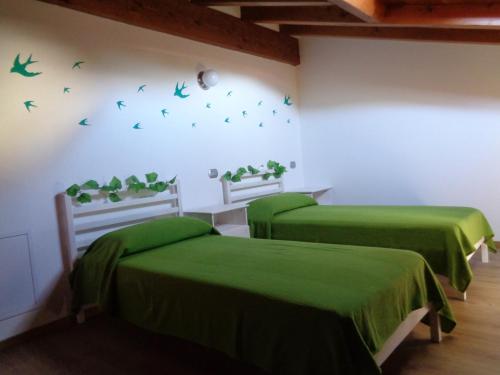 two green beds in a room with birds on the wall at Casa Luce e Aria in Colico