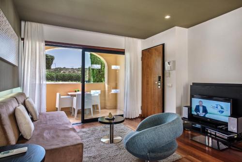 a living room with a couch and a television at Baia da Luz Resort in Luz