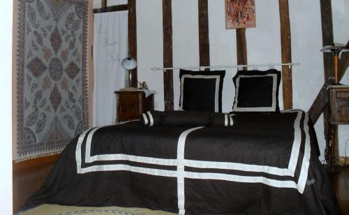 1 dormitorio con 1 cama con manta blanca y negra en La Haute Folie en Le Grand-Lucé