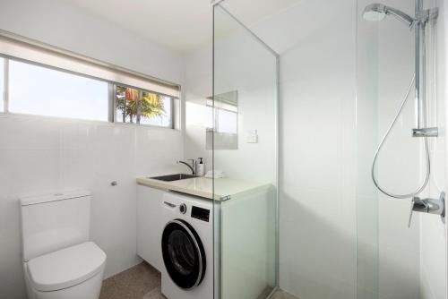 a bathroom with a washing machine and a toilet at The Islander Tropical Noosa Getaway in Noosa Heads