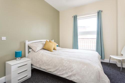 a bedroom with a white bed and a window at Walled City Apartments in Derry Londonderry