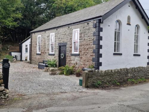 a brick building with a door and a stone wall at The Old Nant-y-Fflint Chapel in Holywell