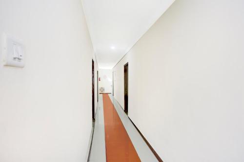 a long hallway with white walls and wood floors at Super Collection O Tirupati Central Junction Formerly Hotel Adith Grand in Tirupati