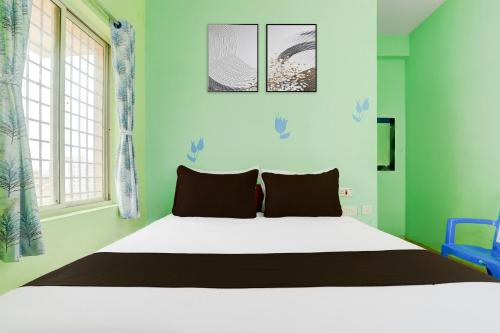 a bedroom with a white bed with green walls and windows at Super Collection O Tirupati Central Junction Formerly Hotel Adith Grand in Tirupati