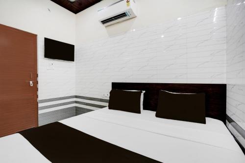 a bedroom with a large white bed with black pillows at Super Hotel O Krishna Janam Bhoomi Formerly Ashirwad Palace in Mathura