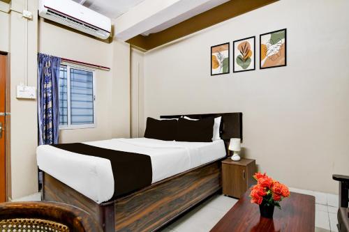 a bedroom with a bed and a vase of flowers at Super Collection O NIT More Adityapur Formerly Hotel Subheksha in Jamshedpur
