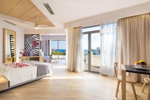 a bedroom with a bed and a view of the ocean at Oscar Suites & Village in Agia Marina Nea Kydonias
