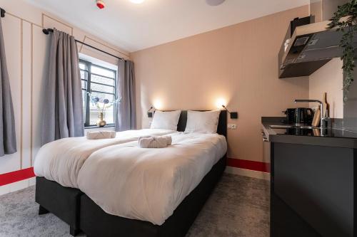 a large bed in a room with a kitchen at Central Tilburg Apartments in Tilburg