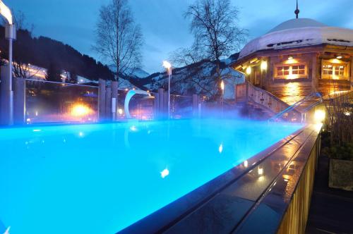 een zwembad met blauwe lichten voor een gebouw bij Stammhaus im Hotel Alpine Palace in Saalbach Hinterglemm