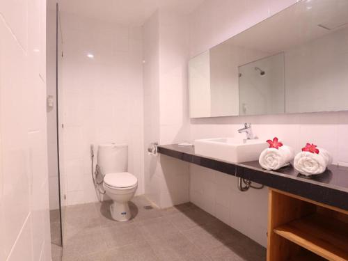 a white bathroom with a toilet and a sink at Fovere Hotel Palangkaraya in Palangkaraya