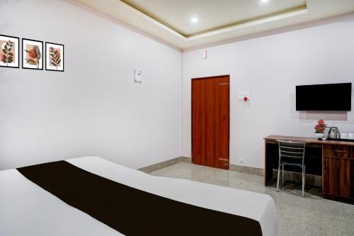 a bedroom with a bed and a desk and a television at Super Collection O Guwahati Airport Formerly Hotel Aniruddha Grand in Kāhārpāra