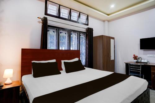 a bedroom with a bed and a desk and window at Super Collection O Guwahati Airport Formerly Hotel Aniruddha Grand in Kāhārpāra
