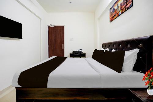 a bedroom with a black and white bed and a television at Townhouse Vangani Railway Station Formerly Hotel Chadha in Neral