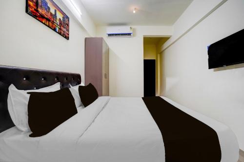 a bedroom with a white bed with black pillows at Townhouse Vangani Railway Station Formerly Hotel Chadha in Neral