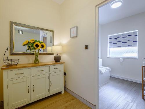 une salle de bain avec un vase de fleurs sur une commode avec un miroir dans l'établissement 2 Bed in Shanklin 78239, à Shanklin