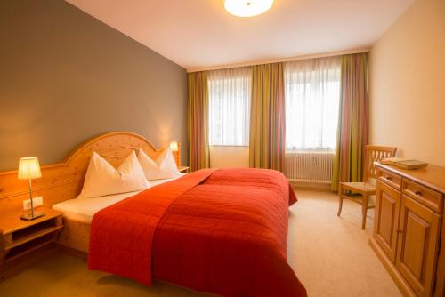 Habitación de hotel con cama roja y ventana en Arcadia Appartments, en Bad Hofgastein